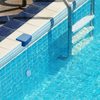 Solar swimming pool light installed on pool edge illuminating underwater
